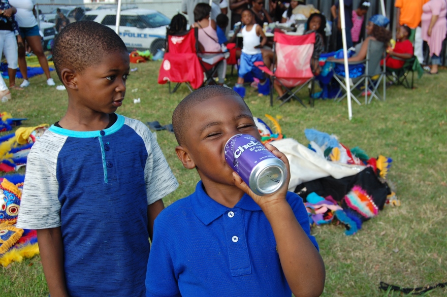 A New Orleans child enjoys a drink while watching the Mardi Gras Indians on Super Sunday 2016.